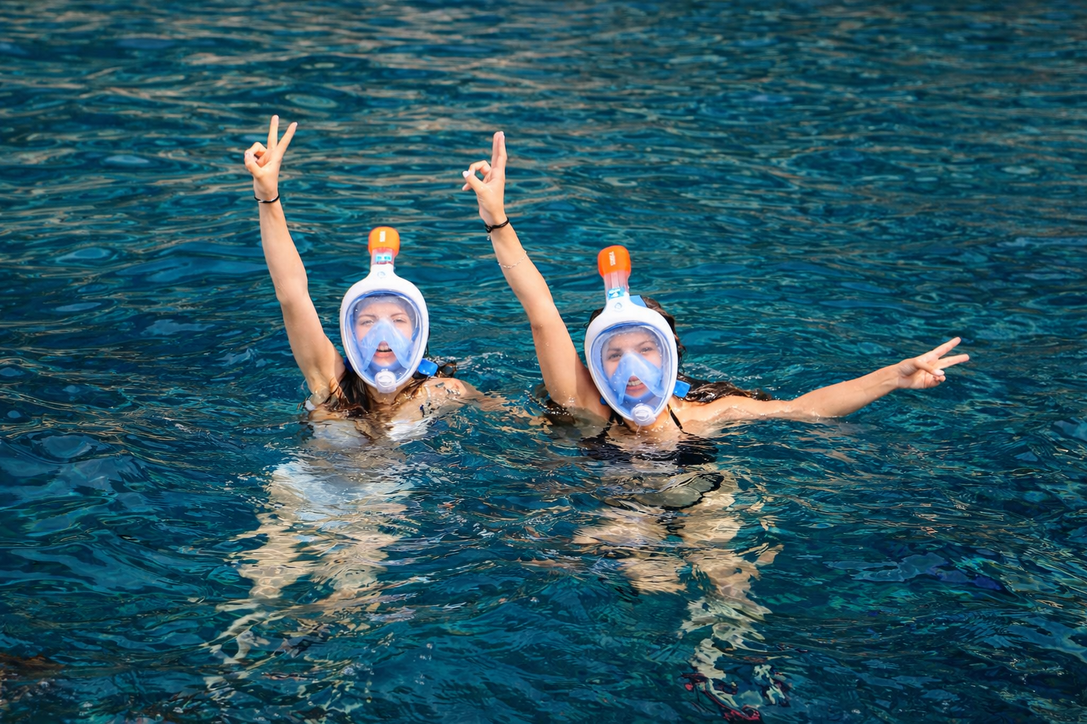Two friends enjoying snorkeling in crystal clear water during a boat trip in Puerto de Mogan Gran Canaria